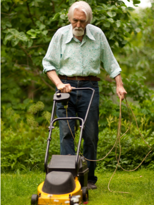 A man uses an electric mower with outdoor extension cord